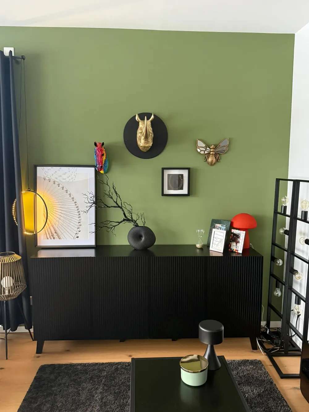 Wohnzimmerwand in Olivgrün, davor ein schwarzes Sideboard