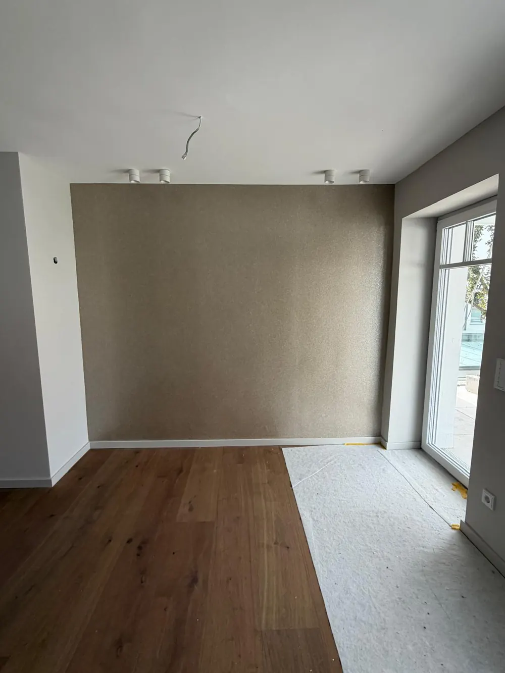 Wand mit sandfarbener Strukturtapete in einem Neubau